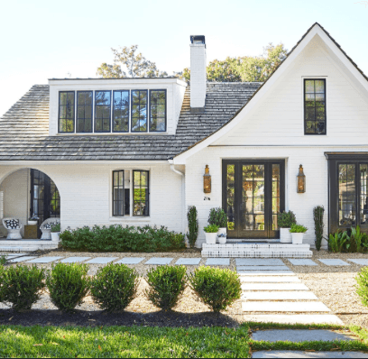 White Brent Realty home with black-framed windows and landscaped front walk